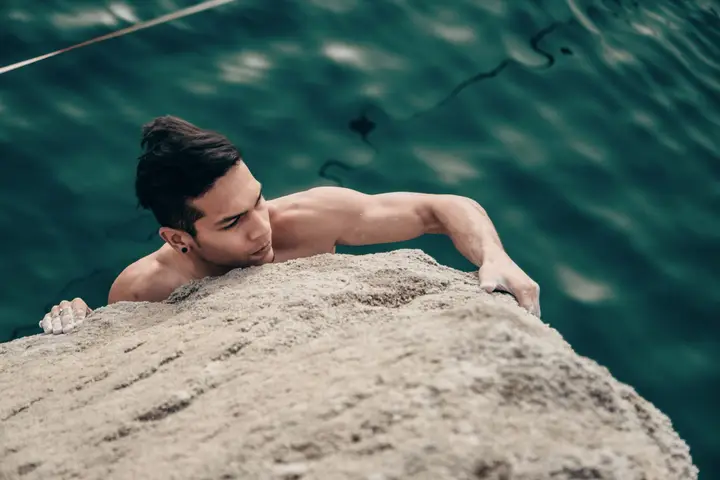 Varun topping out a boulder on a lake.