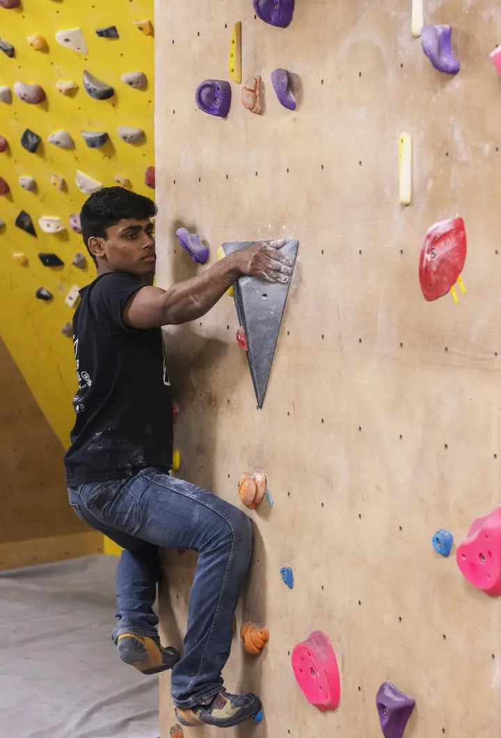 Arjun using a volume as a handhold in a blue climb.
