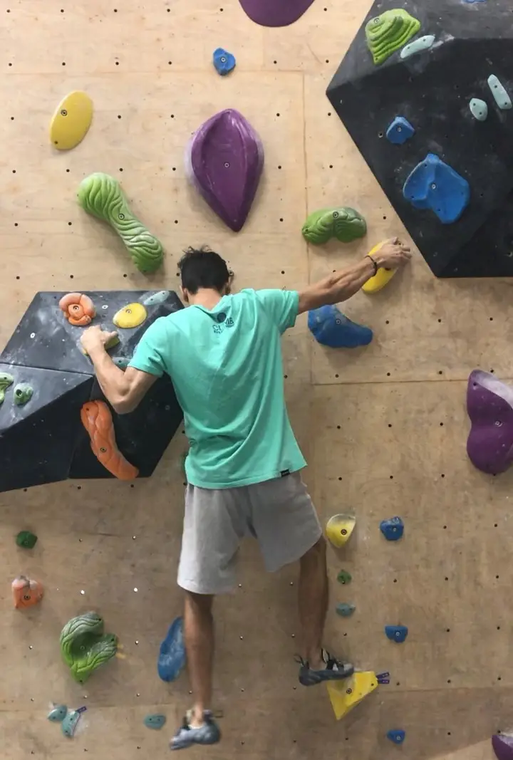 Varun side-pulling on a hold towards his right.