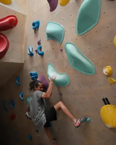 A woman climbing a colourful wall at BoulderBox