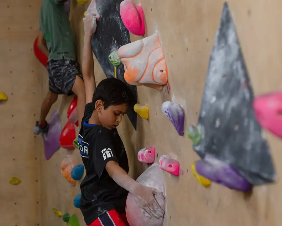 A coach guides a young climber on the wall