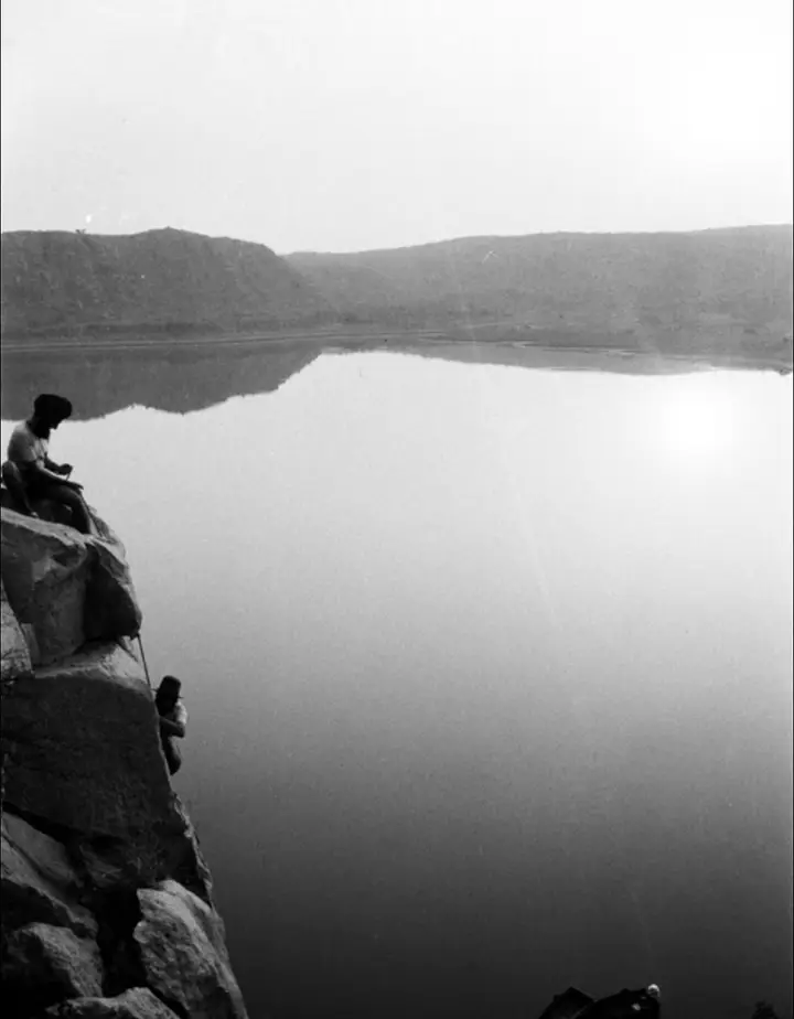 Climbers from back in the days sitting atop a rock face overlooking the lake.